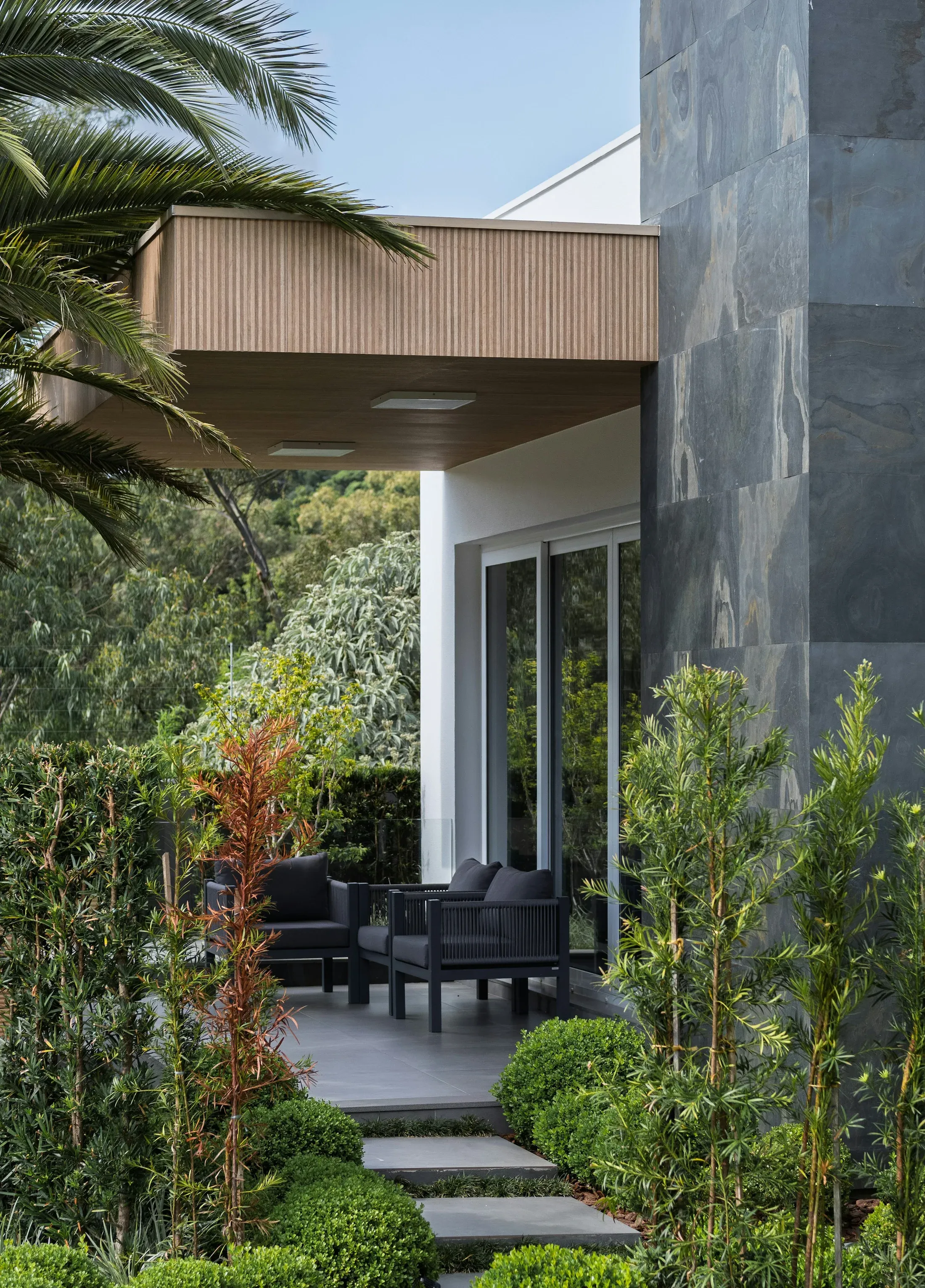 A sheltered contemporary patio with outdoor seating and lush planting
