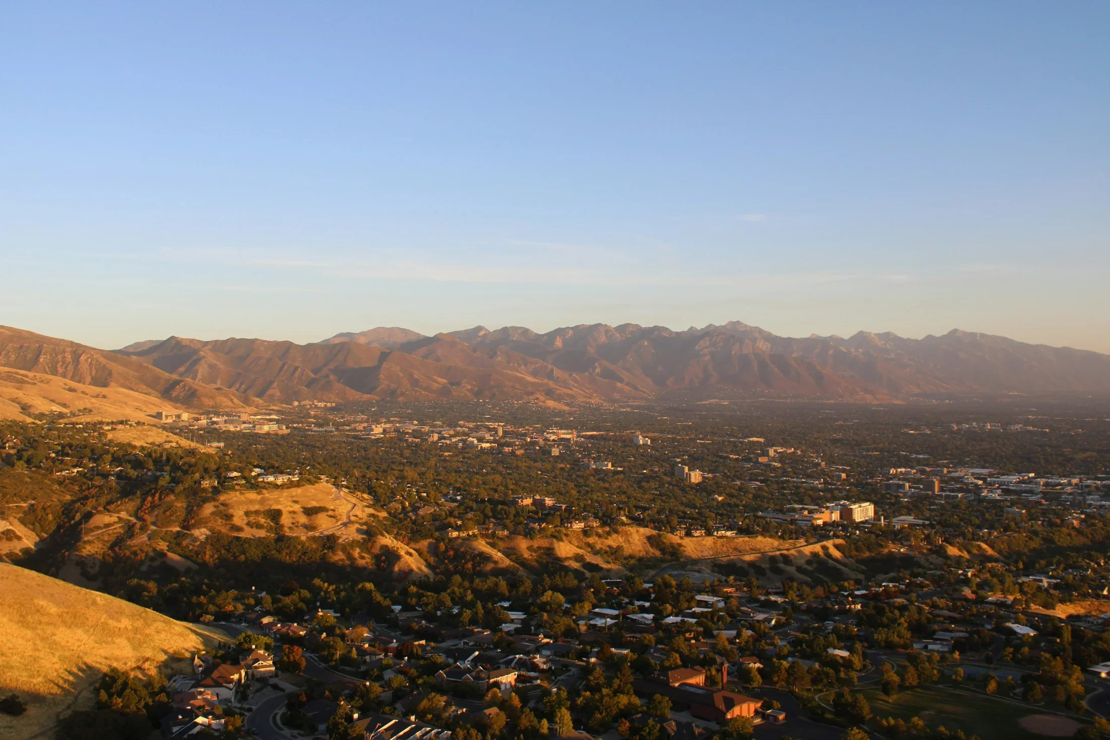 Golden foothills above Salt Lake City neighborhoods and the distant mountains